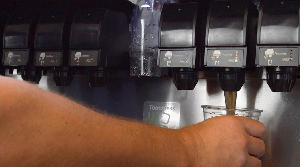 Person pouring soda from a beverage dispenser