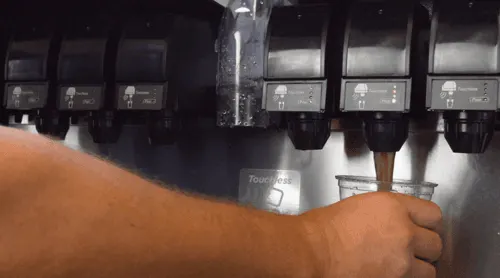 Person pouring soda from a beverage dispenser