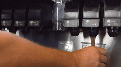Person pouring soda from a beverage dispenser